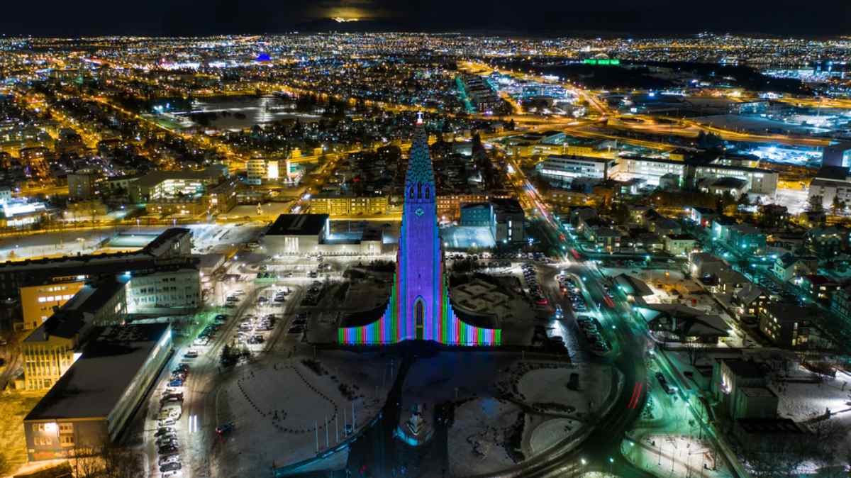 Vista de dron de la ciudad de Reikiavik durante la noche en lo que parece la proyección de las luces del festival Winter Lights Festival sobre la catedral de Hallgrímskirkja.
