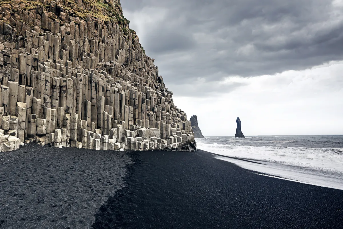 Panoramic view of Iceland's stunning black sand beaches, contrasting with the dramatic waves and rugged coastal cliffs