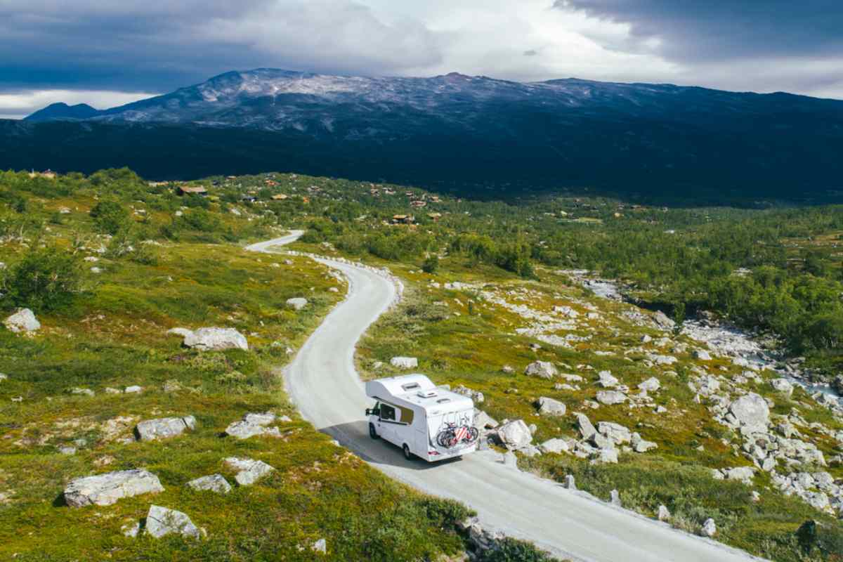 Motorhome driving along a winding mountain road through a wide green landscape