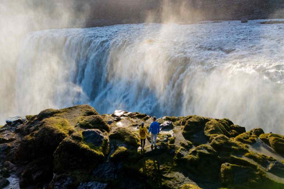 Wide view of Gullfoss waterfall with walking paths and visitors on the cliffs