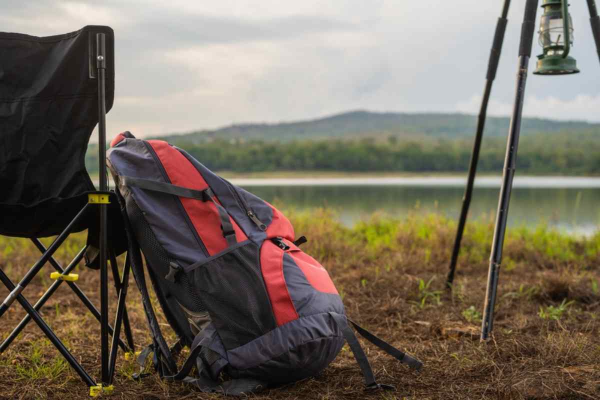 What to pack for camping in Iceland Camping essentials by a lakeshore: backpack, folding chair and lantern, showing what to pack for an Iceland camping trip.