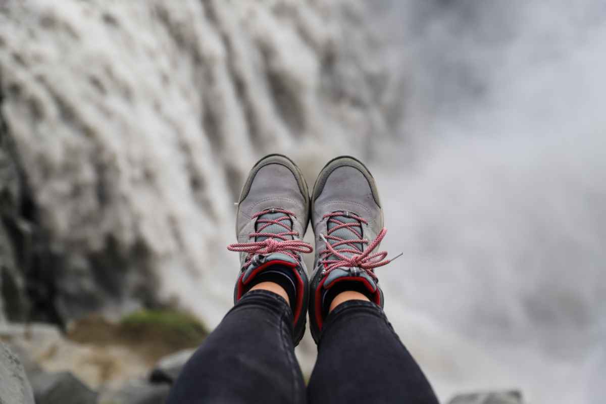 Hiking boots resting above a blurred waterfall in Iceland.