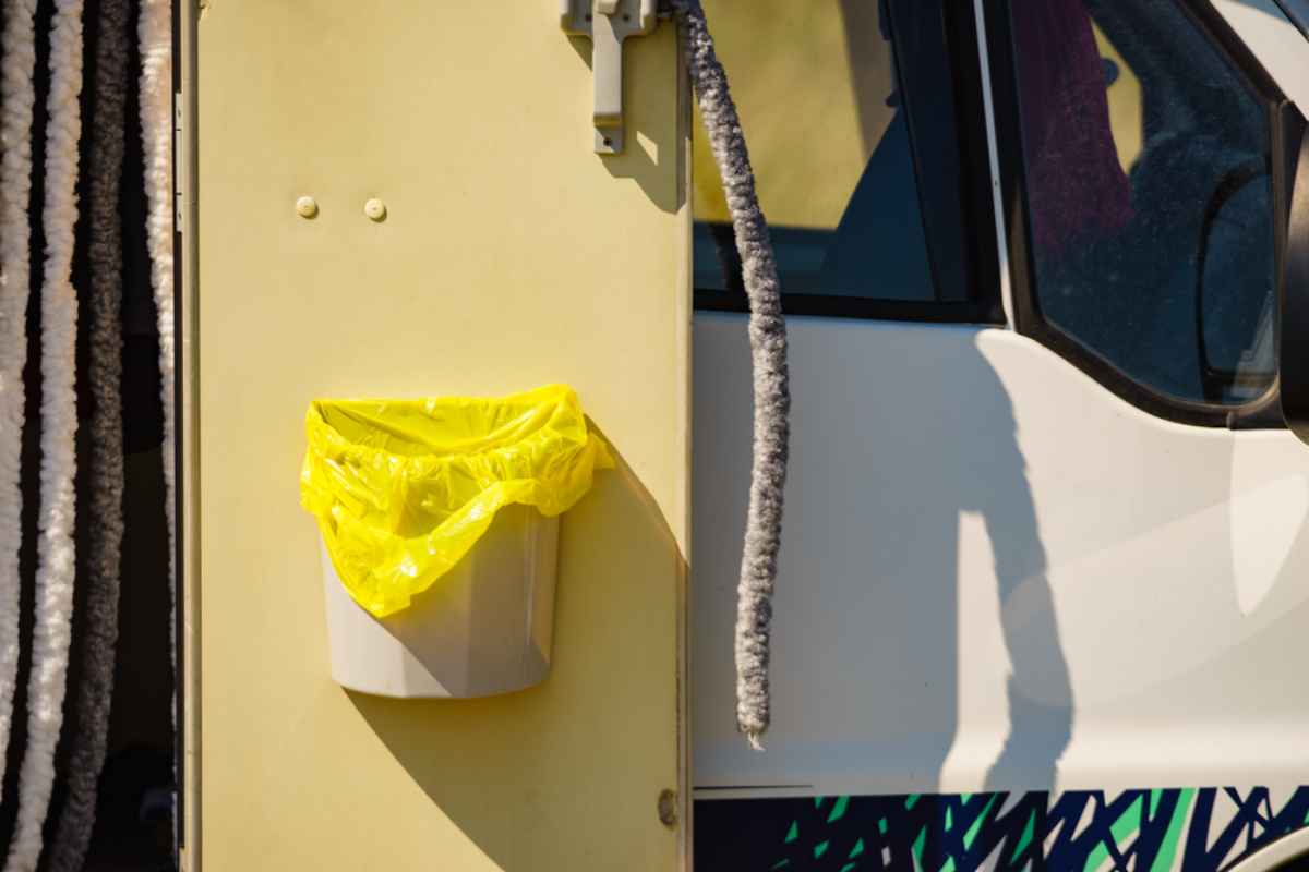 Small trash bin attached to the inside of a campervan door.