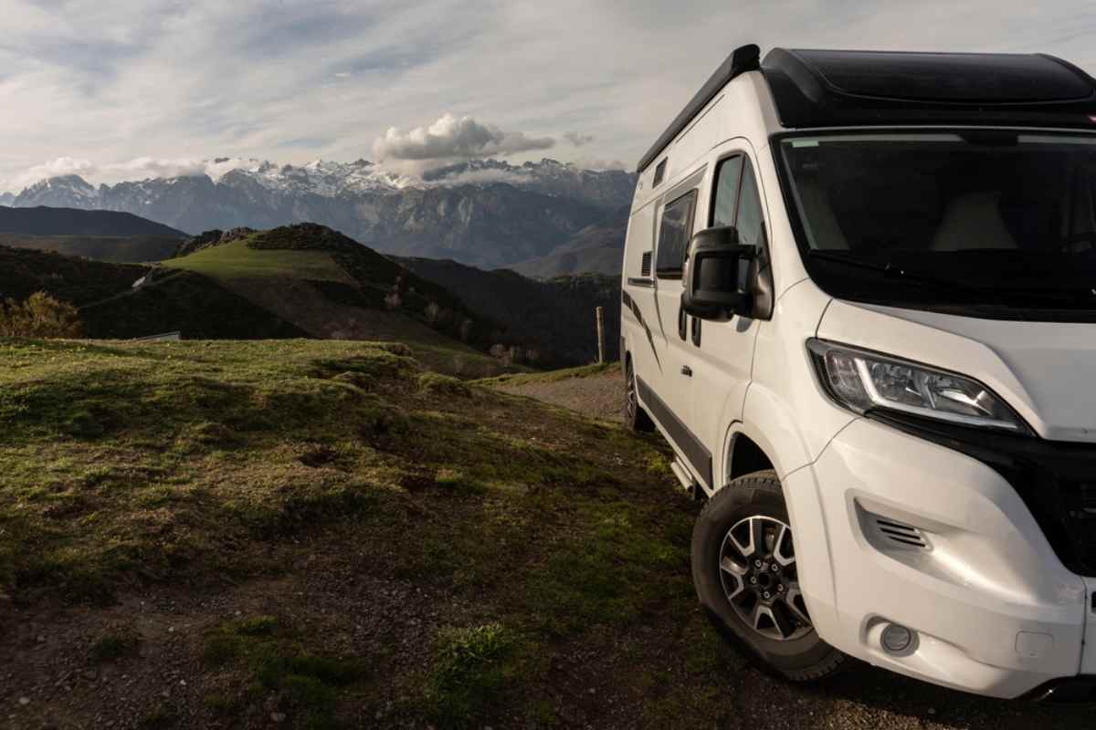 A white 4x4 campervan remains parked in Iceland in a completely irregular Icelandic landscape with multiple elevations.