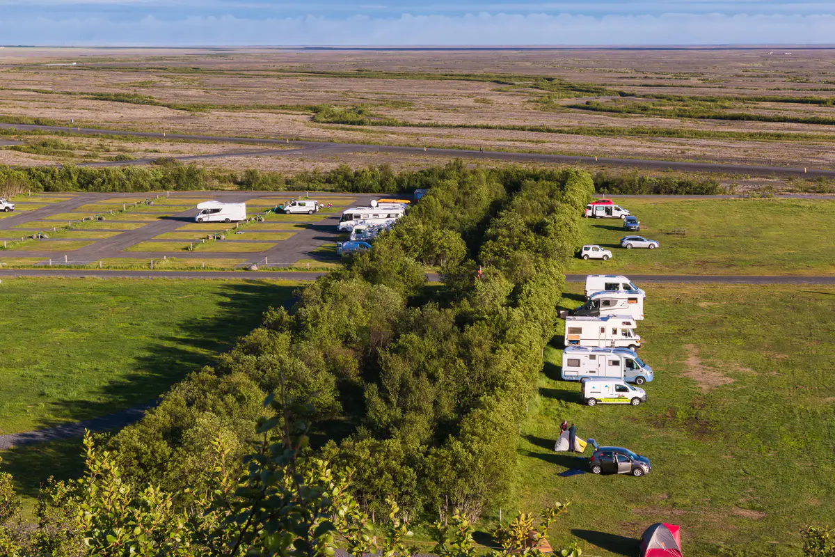A well-maintained campervan campground in Iceland, featuring designated parking spots, green spaces, and various campervans parked—highlighting some of the best sites for campervan travelers.
