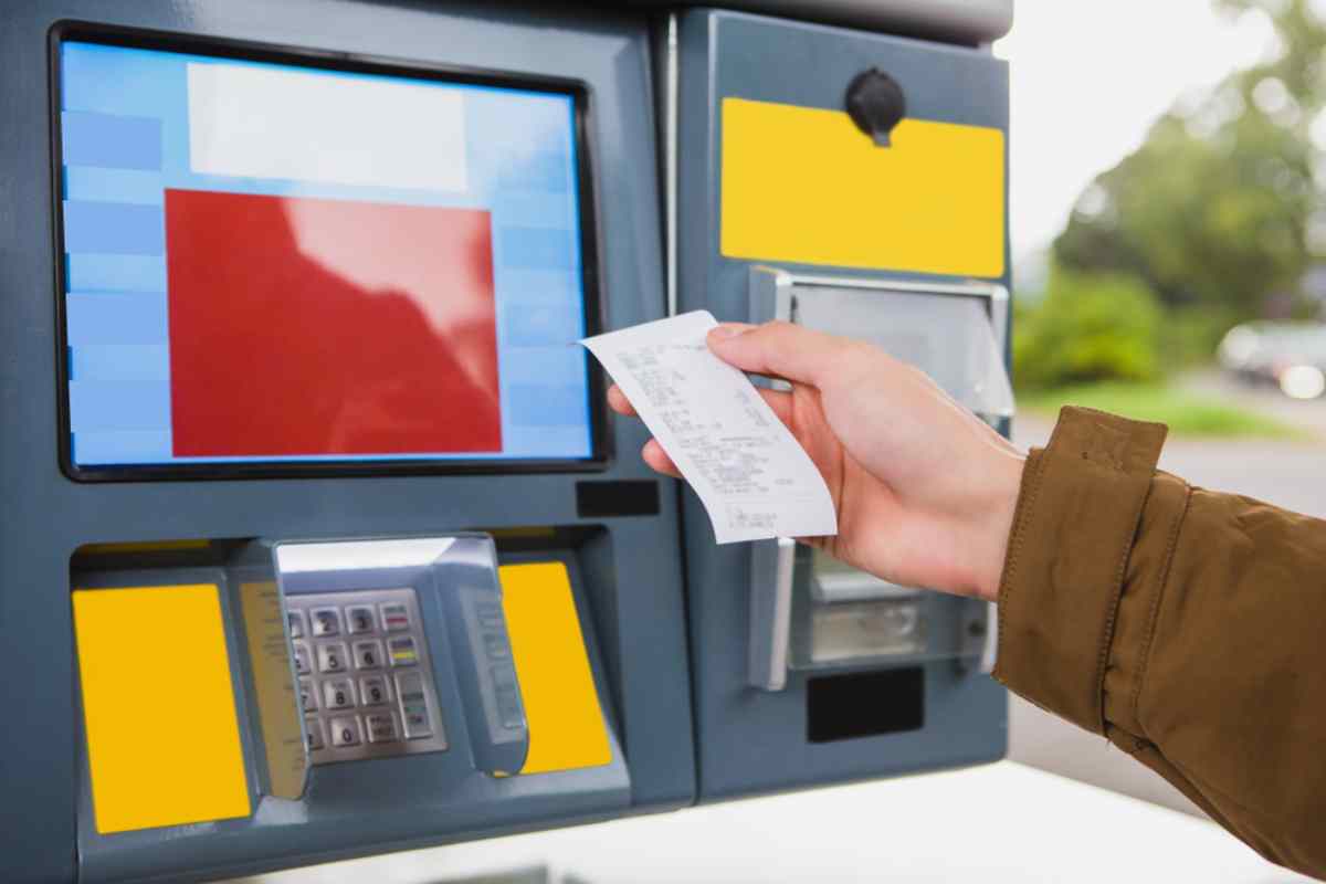 Hand holding a printed receipt from a gas station payment machine.