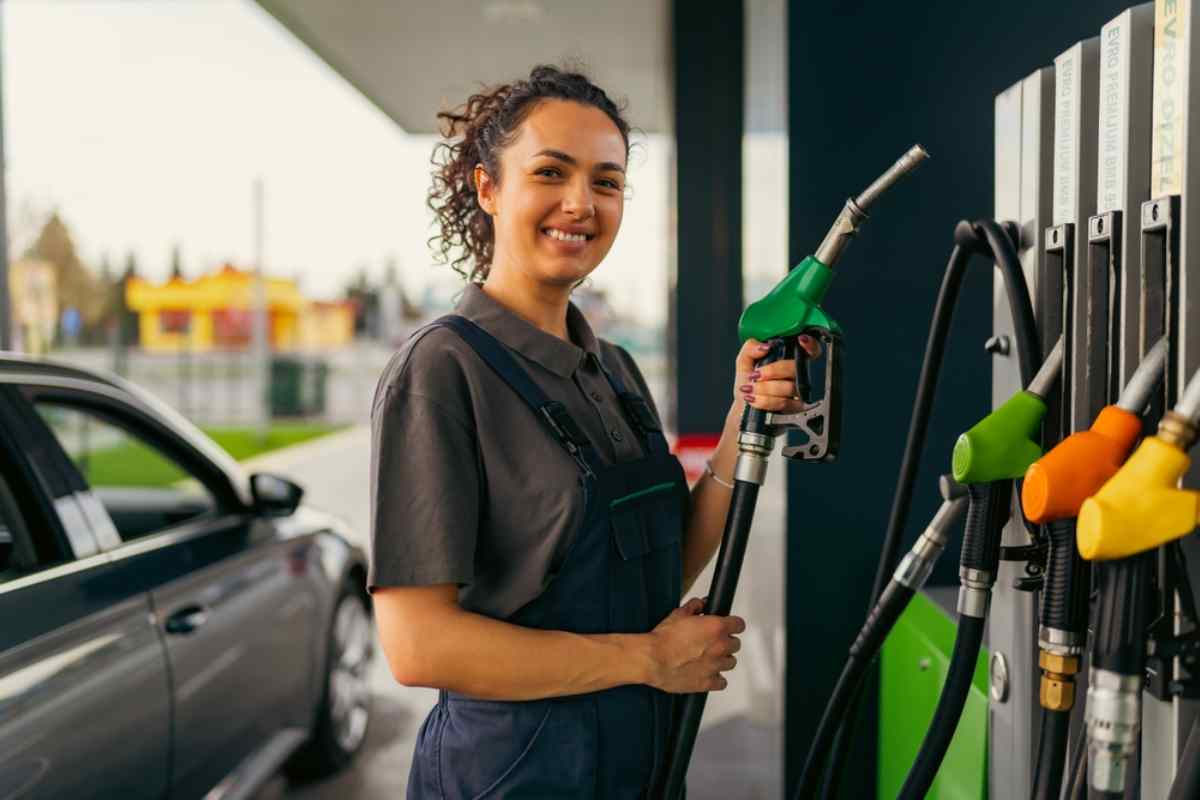 Smiling worker holding a fuel pump at a gas station in Iceland.