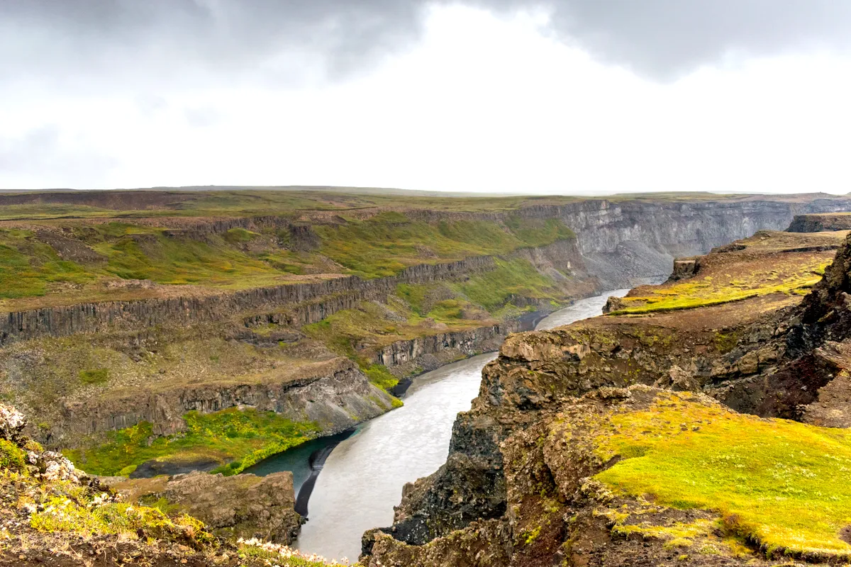 A vast view of J&ouml;kuls&aacute;rglj&uacute;fur Canyon in Iceland with rugged cliffs and the river flowing through the valley