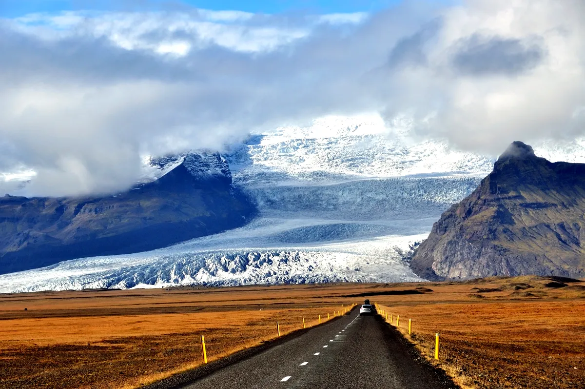 A car driving towards the massive Vatnaj&ouml;kull glacier, Iceland&rsquo;s largest ice cap, with mountains towering in the background.