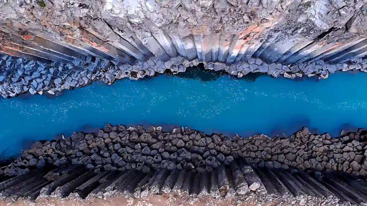 Aerial view of Studlagil Canyon showcasing its turquoise river and basalt formations.