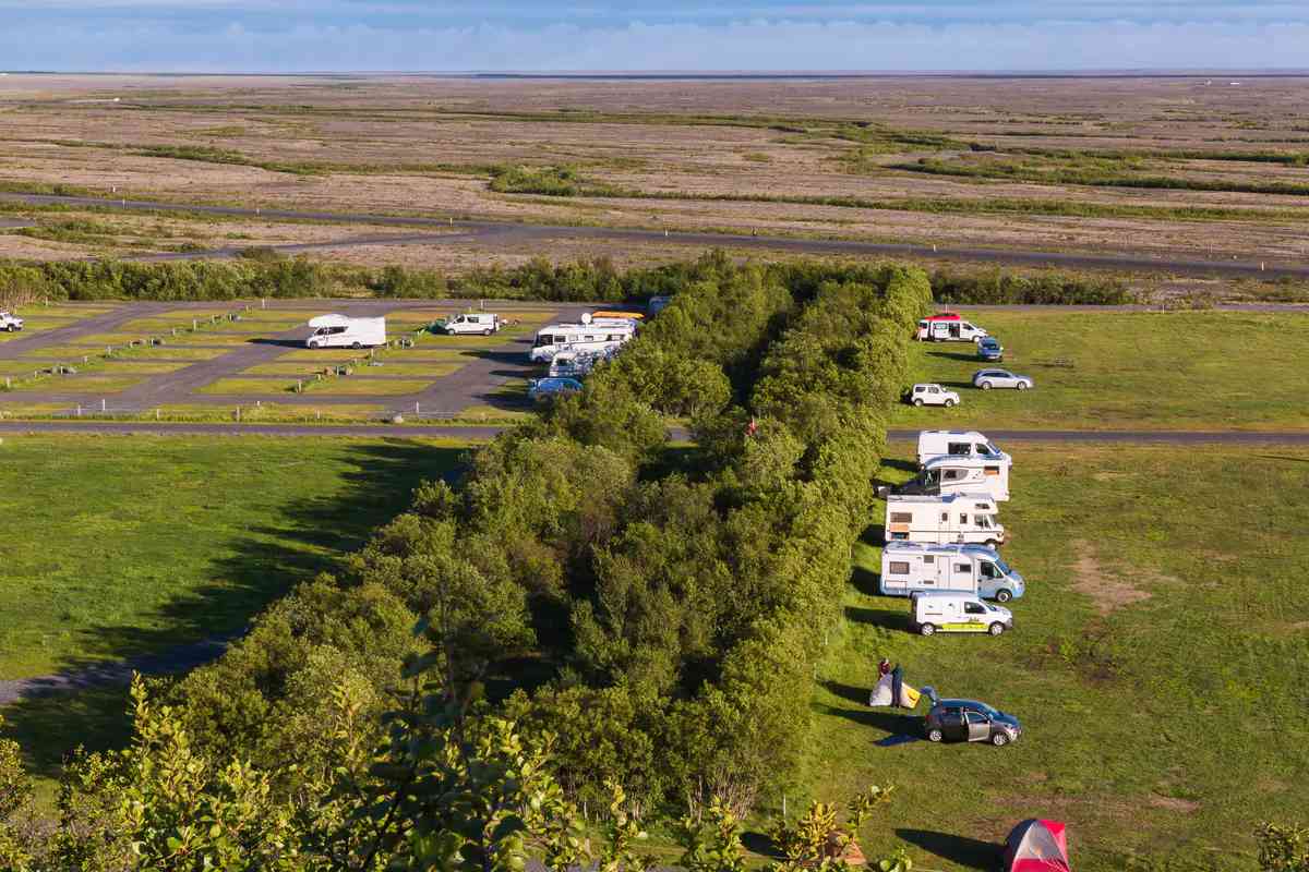 Un camping bien mantenido en Islandia con áreas designadas para campervans, espacios verdes y varias campervans estacionadas, destacando algunos de los mejores sitios para viajeros en campervan.