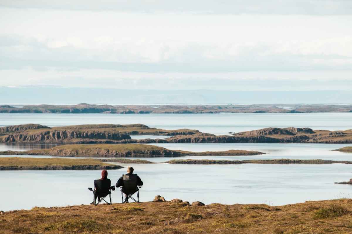 Two campers enjoying the wonderful landscapes of Iceland while sitting on foldable camping chairs