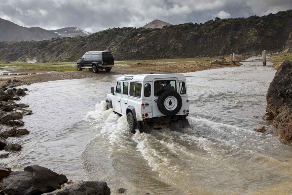 A pair of 4x4 cars drive through a waterlogged area in the Icelandic Highlands.