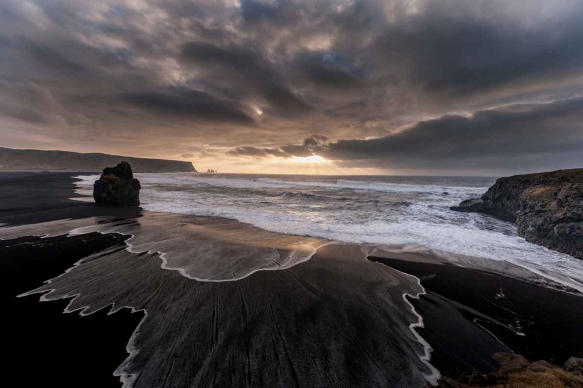 Iceland's Reynisfjara black sand beach during a gloomy, dusk day.