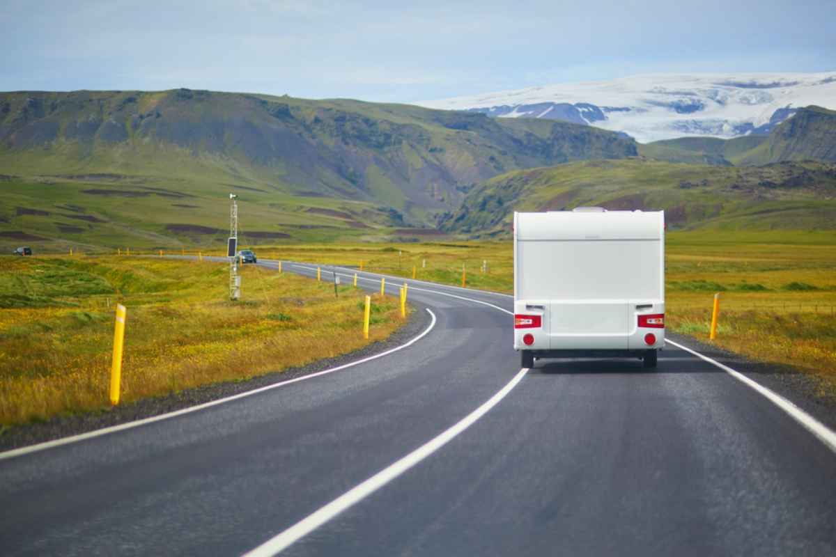 Un camping-car blanc roule librement sur une route dégagée et colorée de la Route circulaire en Islande.