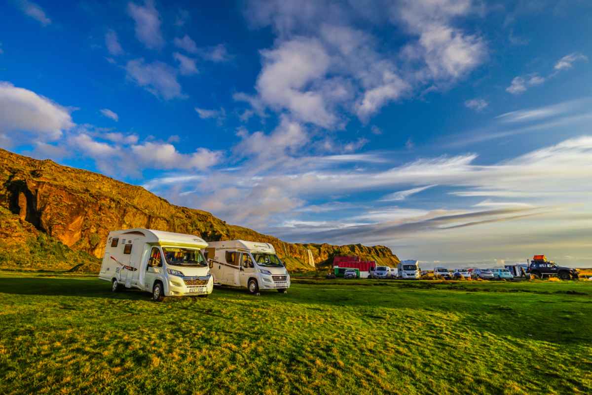 Un groupe de camping-cars stationnés dans une prairie verte islandaise, aménagée pour ce type de séjour.