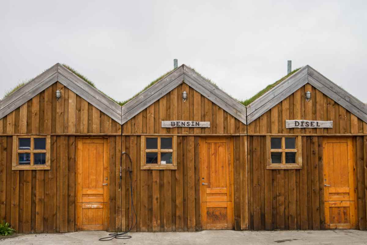 Station-service traditionnelle islandaise avec différentes cabines en bois selon le type de carburant. Dans ce cas, essence et diesel sont différenciés par des inscriptions en islandais.