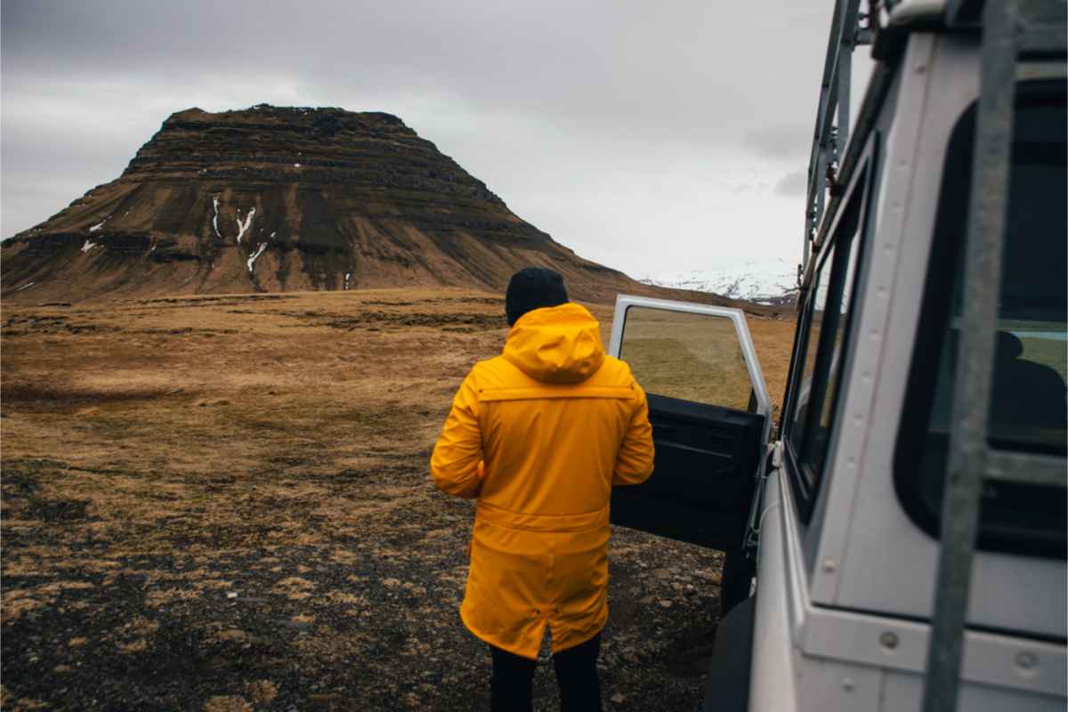 Tourist in a yellow jacket standing right by his 4x4 camper in Iceland's highlands