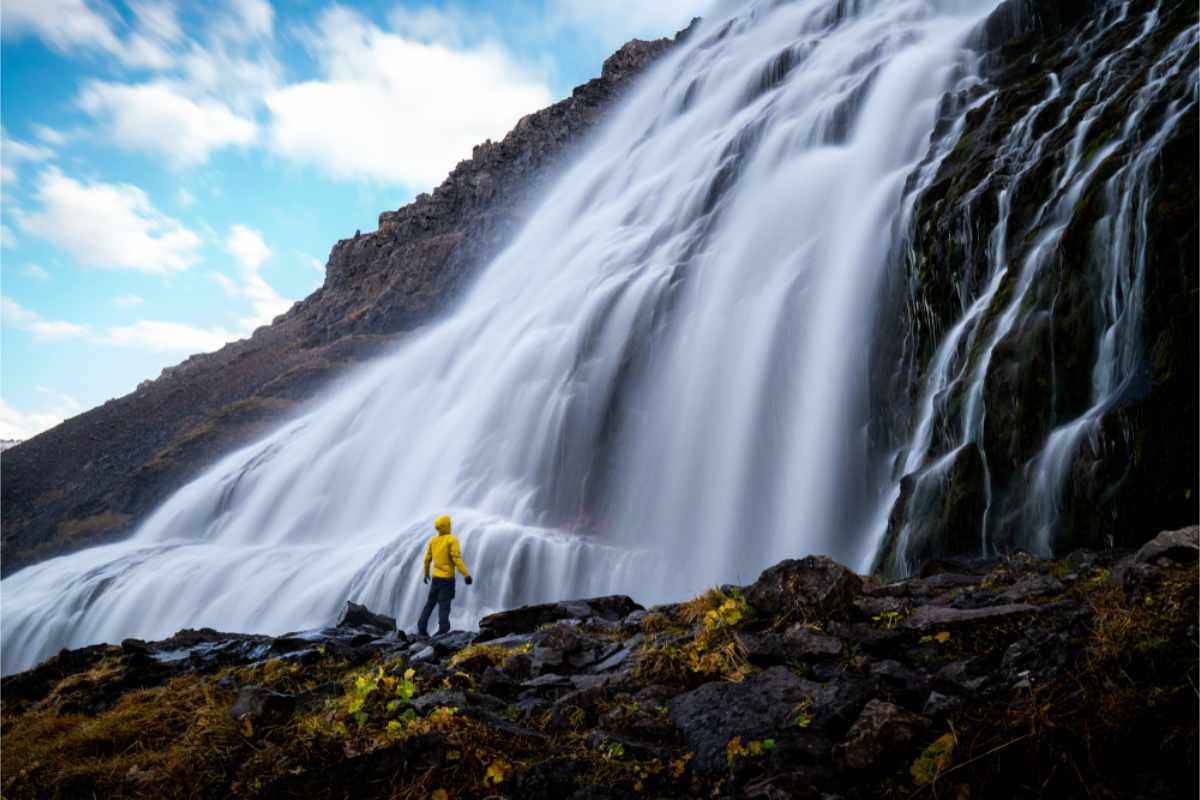 Tourist standing right by Dynjandi waterfall in the Westfjords