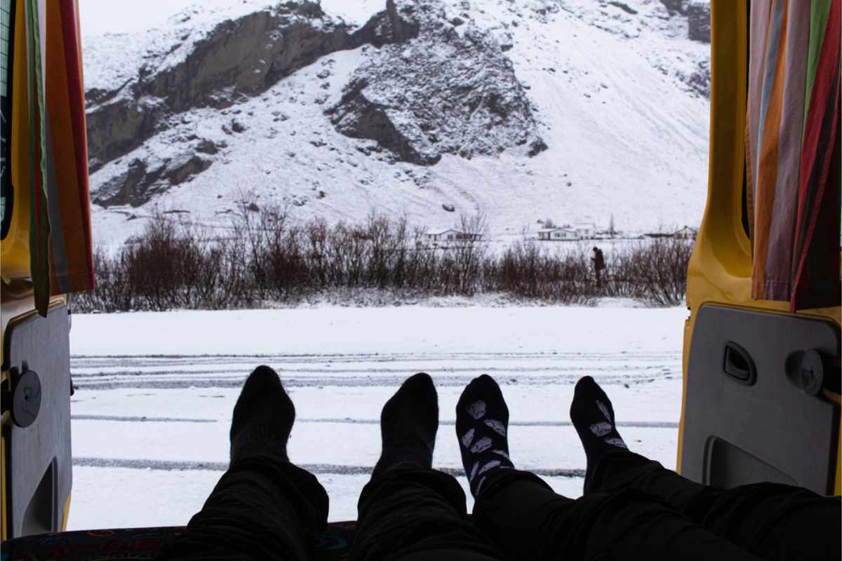 Campers sticking their feet out of their camper to a snow covered landscape
