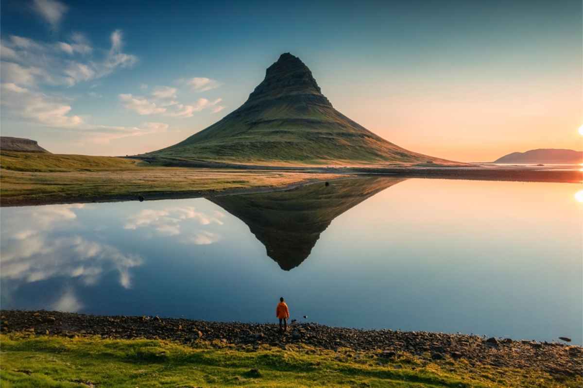 A beautiful symmetrical shot of Kikfjufell mountain at dusk with a tourist right in the middle.