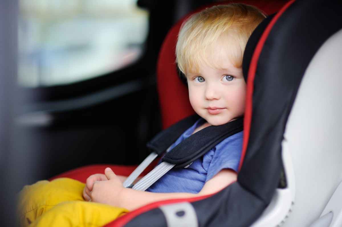 Blonde baby seating in his child seat in the van's rear row