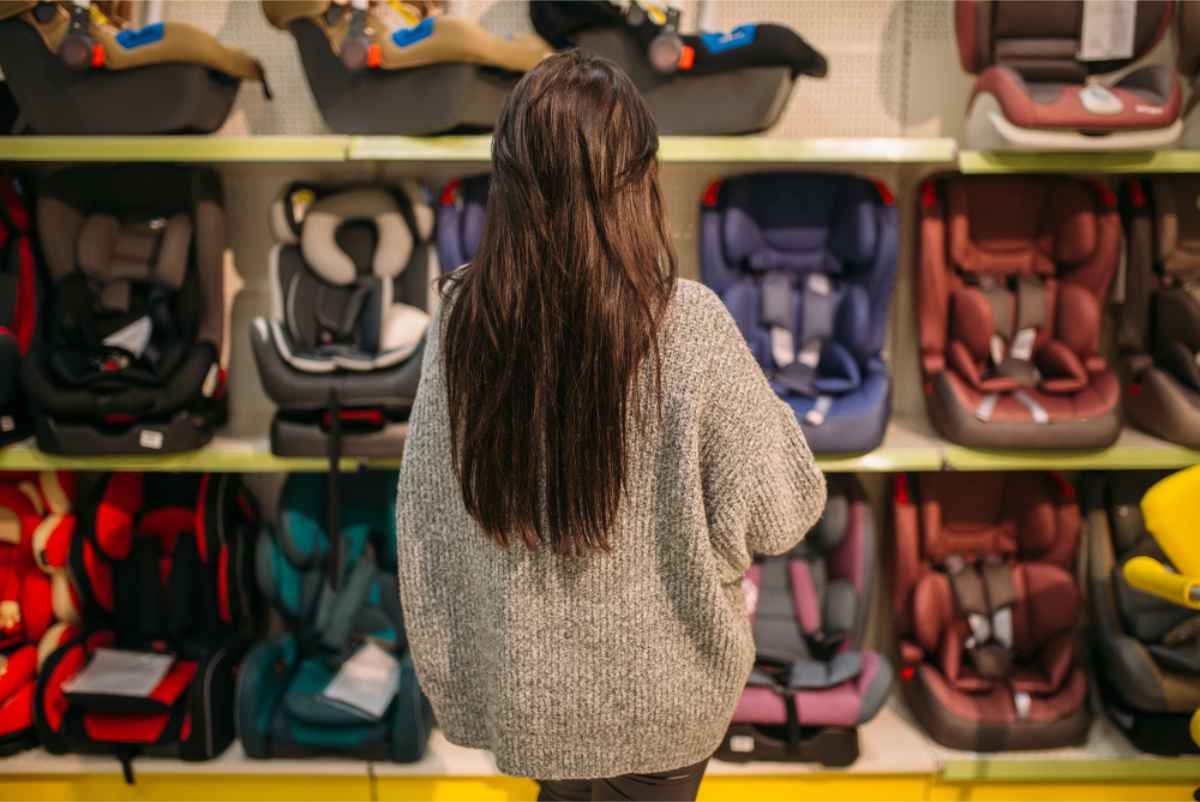 woman in front of several child seats in a store