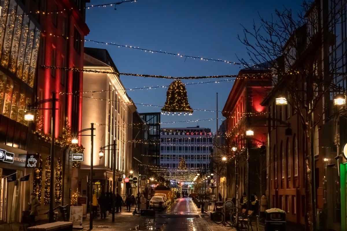 Downtown Reykjavik street at dusk decorated with Christmas lights and a bell-shaped garland.