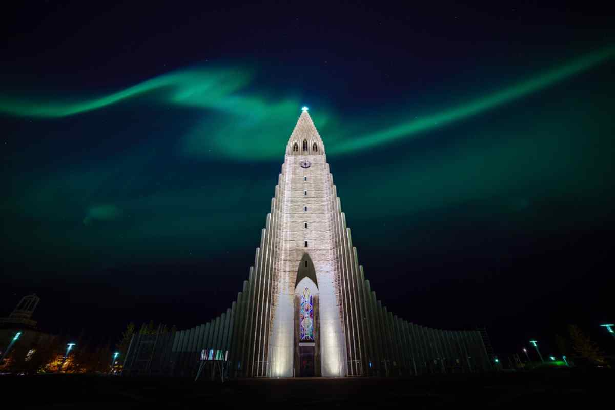 Northern lights arching over Hallgrímskirkja church in Reykjavik at night.
