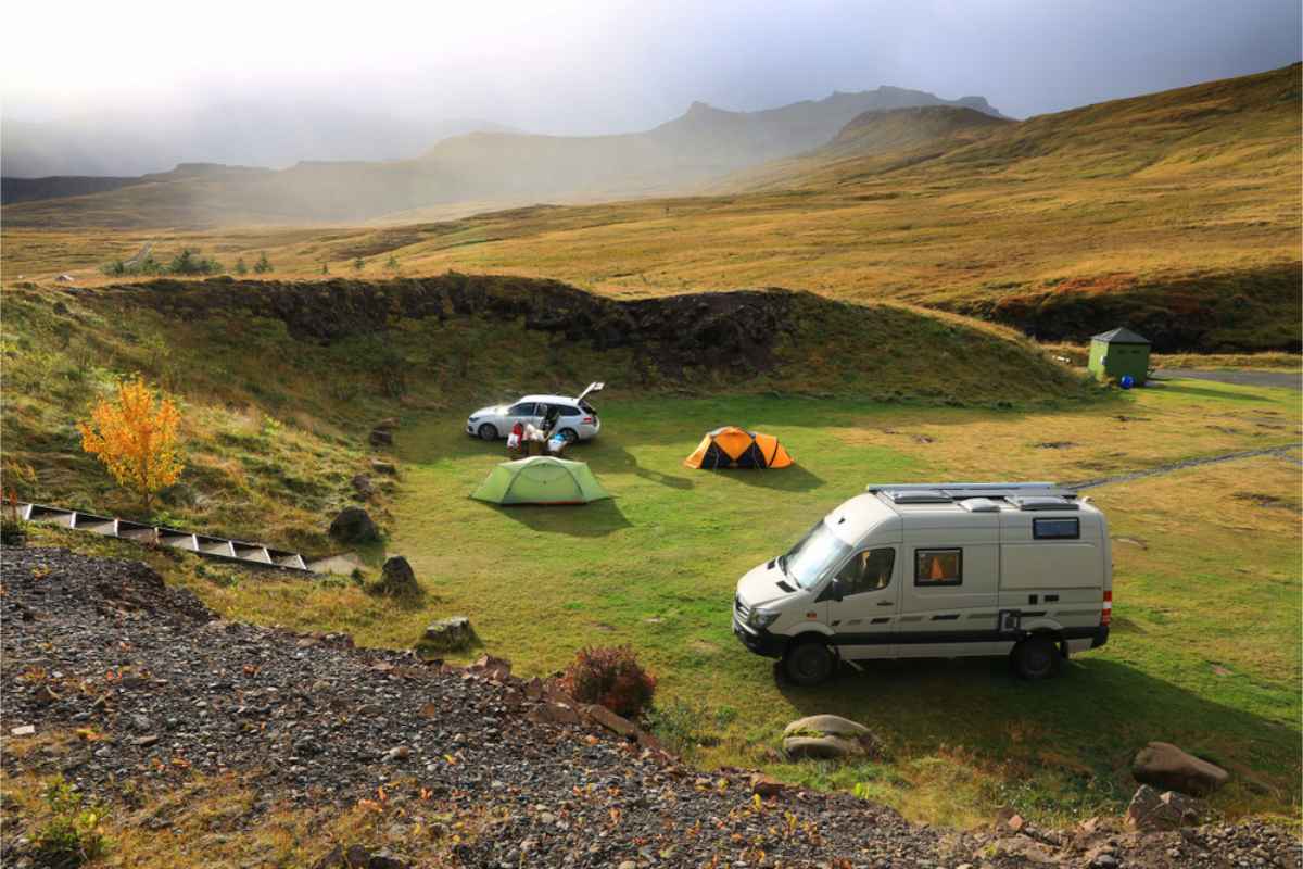 4x4 motorhome parked at a campsite along with some tents and a 2WD vehicle