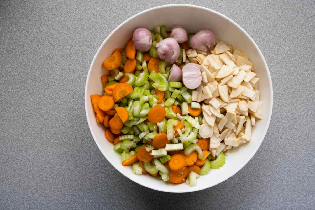 Bowl of prepped veggies—carrot, celery, parsnip, and shallots—ready for foil-pack cooking.