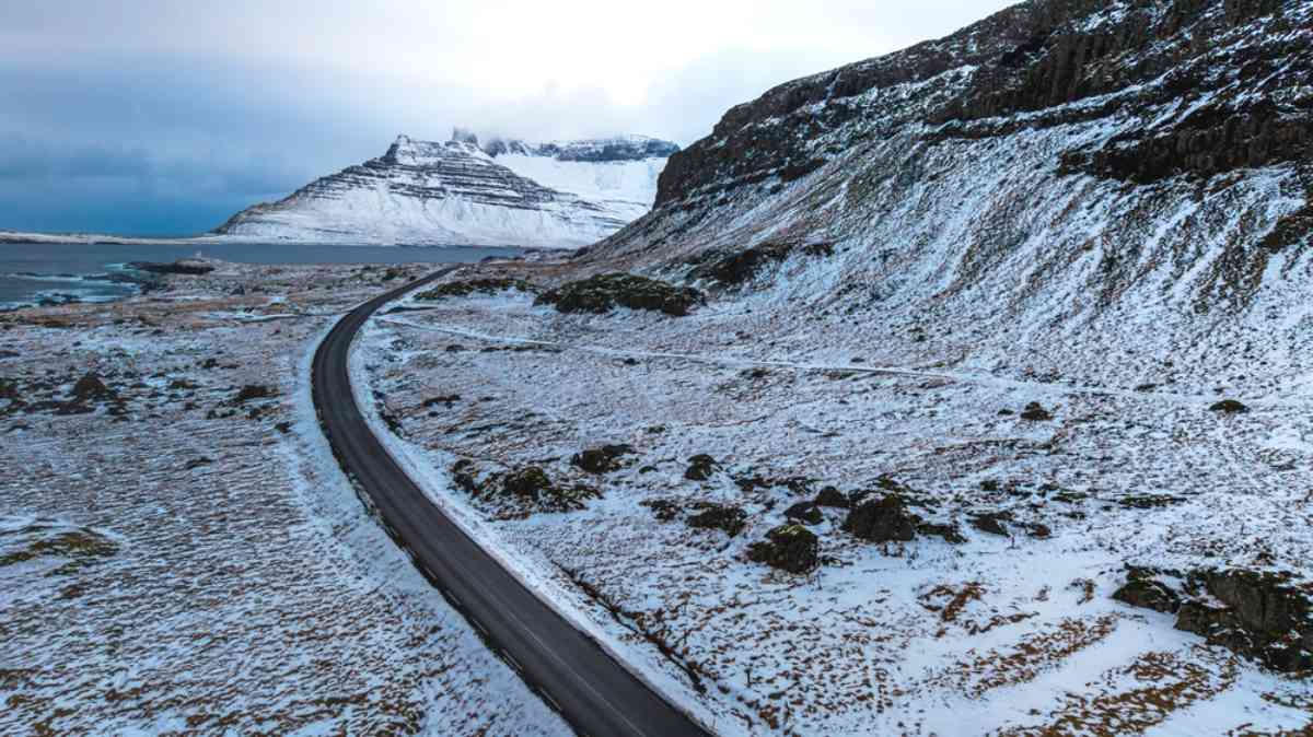 Icy road in Iceland Winter Ring Road in Iceland with icy pavement winding past snow-dusted mountains and coastline.