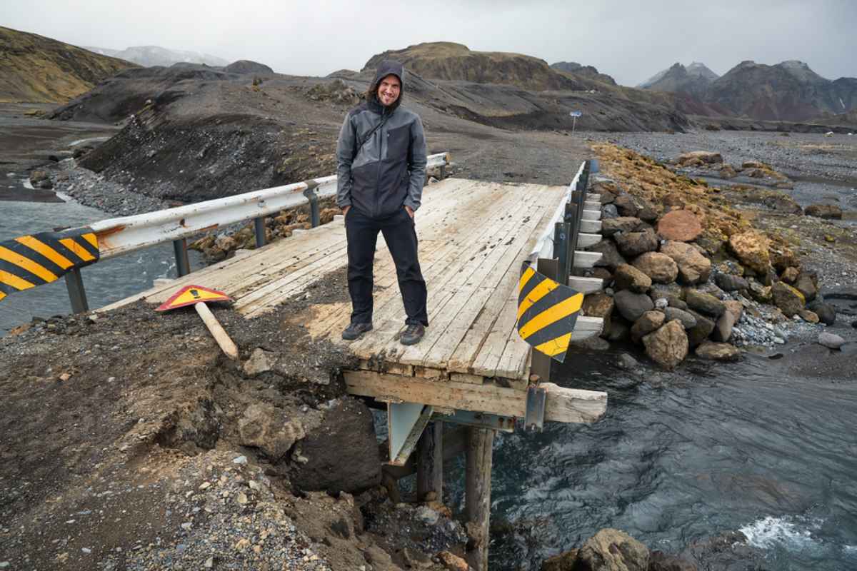 Incomplete road in Iceland Traveler standing at a washed-out single-lane bridge in Iceland, highlighting incomplete or damaged roads.