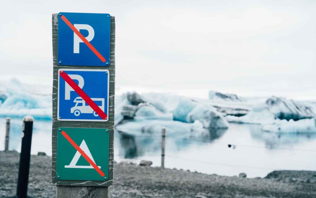 Pannelli che vietano parcheggio, sosta in camper e campeggio vicino a una laguna glaciale islandese.