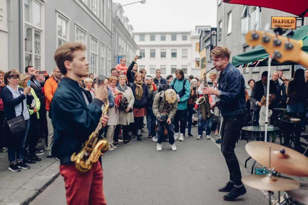 Musicisti con sax suonano in una strada di Reykjavík davanti a una folla durante un evento cittadino.