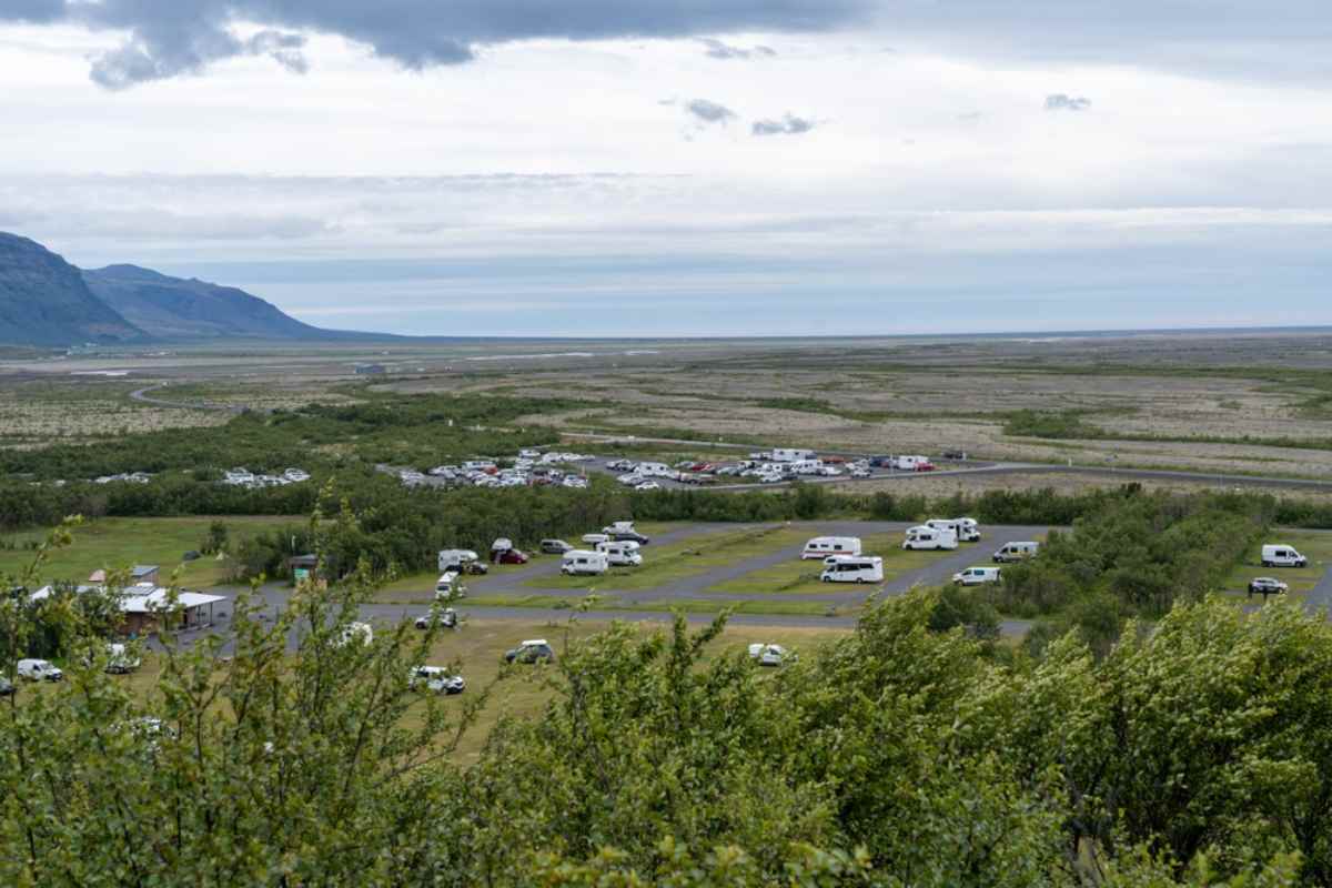 Aerial view of the campsite in Vatnajökull National Park, where a multitude of campervans and RVs can be seen from afar in a landscape full of vegetation.