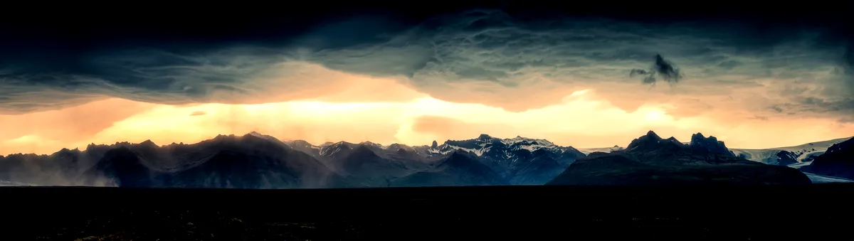 Nubes oscuras con puesta de sol sobre una cadena monta&ntilde;osa islandesa