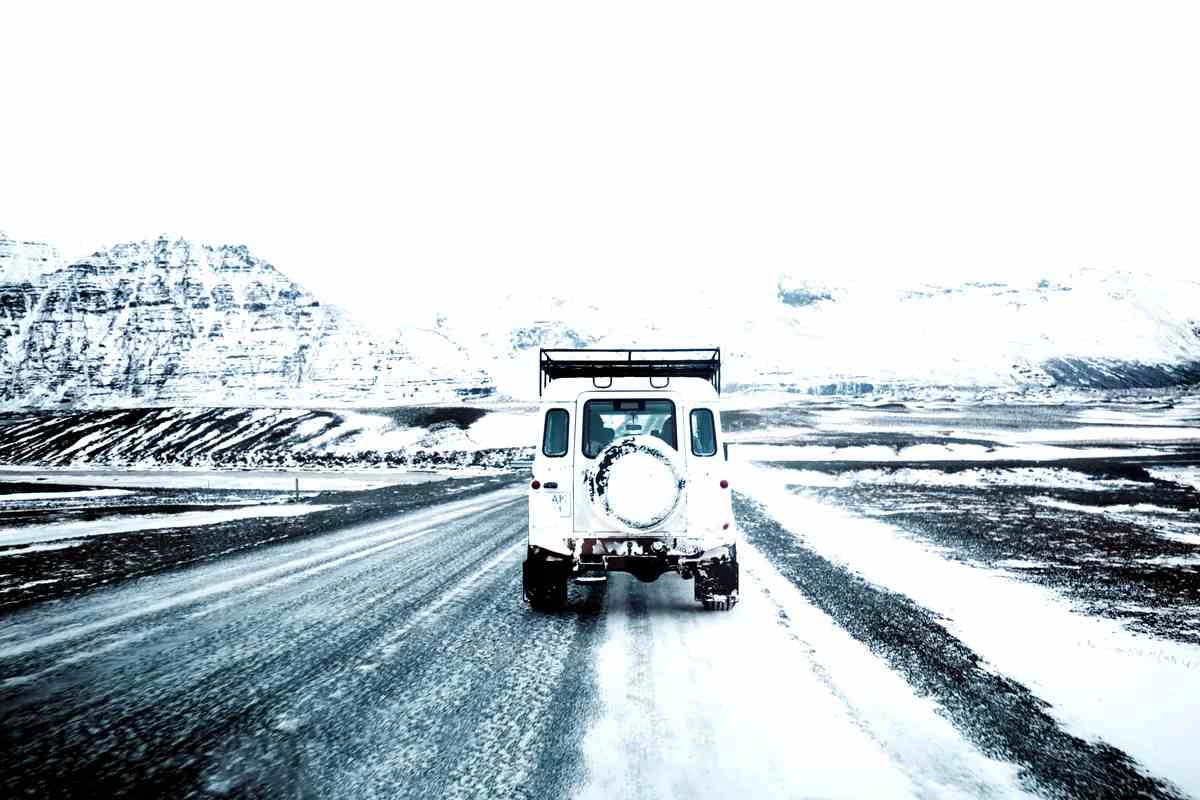 Veh&iacute;culo 4x4 circulando por una carretera helada en un paisaje island&eacute;s cubierto de nieve