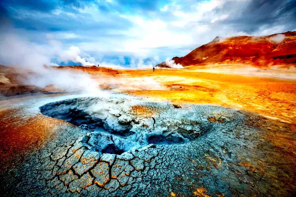 Zona geot&eacute;rmica con fuentes termales humeantes y terreno colorido en Islandia.