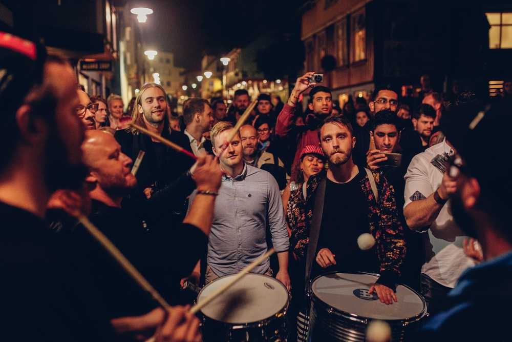 Street drummers performing at night as a crowd watches during a lively summer festival in Iceland.