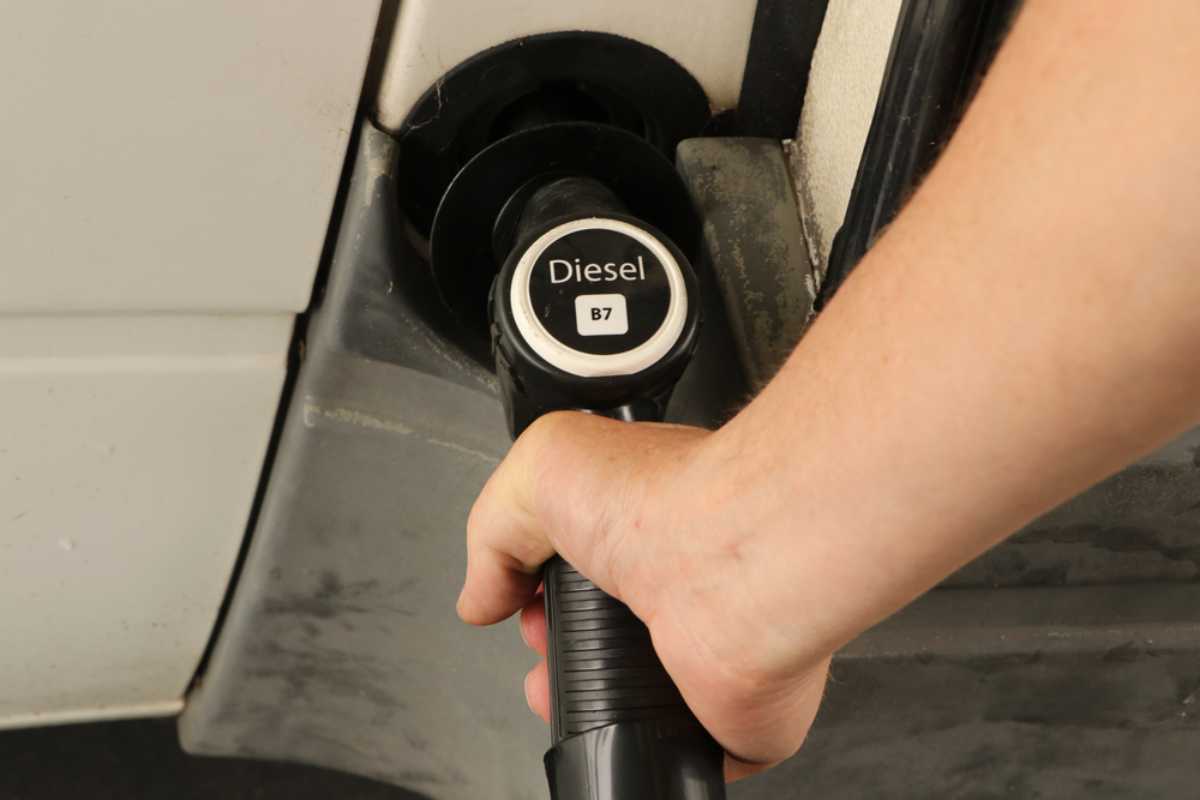 Hand holding a diesel fuel pump nozzle while refueling a vehicle in Iceland
