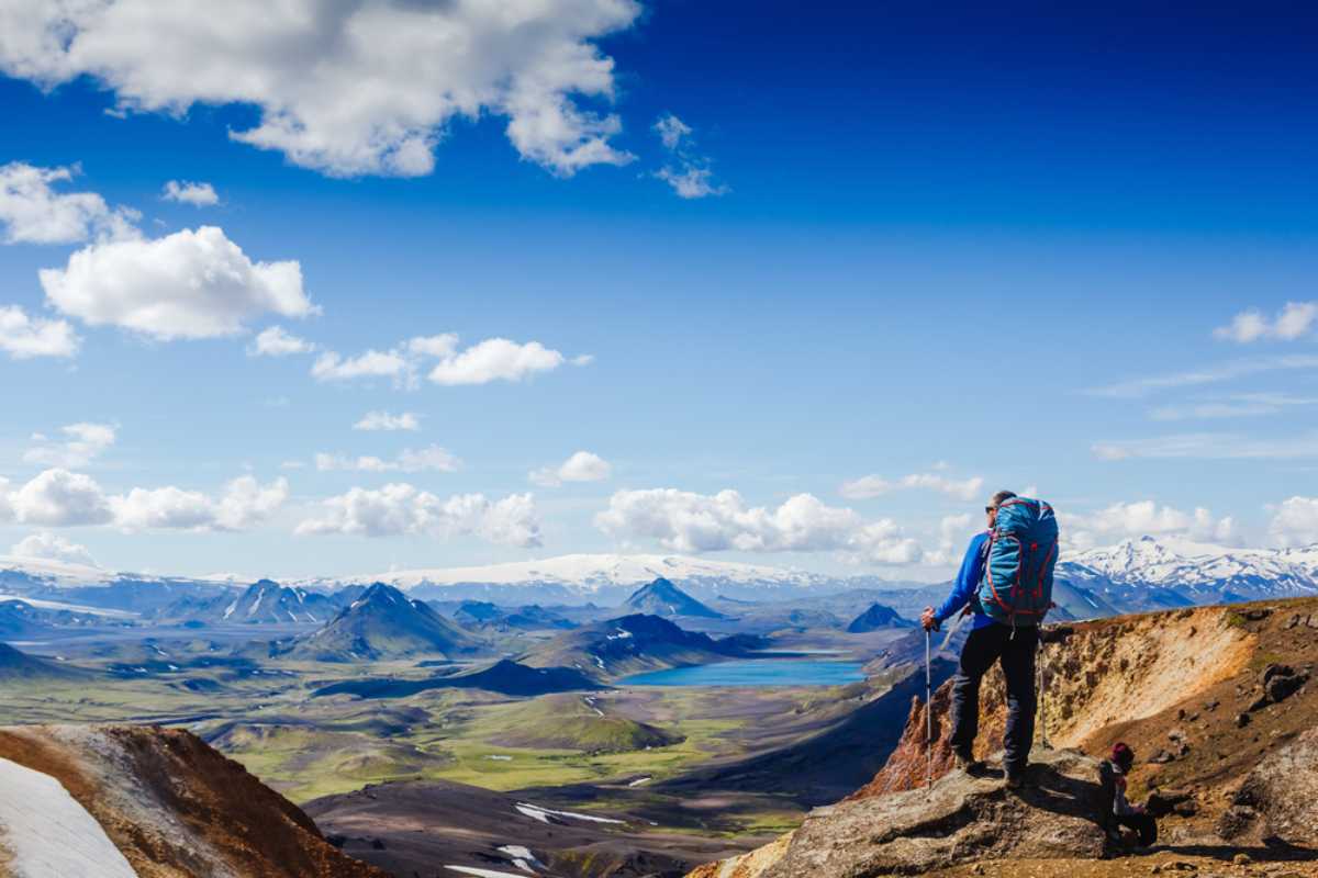 Hiker overlooking Iceland&rsquo;s colorful highlands with mountains, lakes, and wide volcanic valleys below