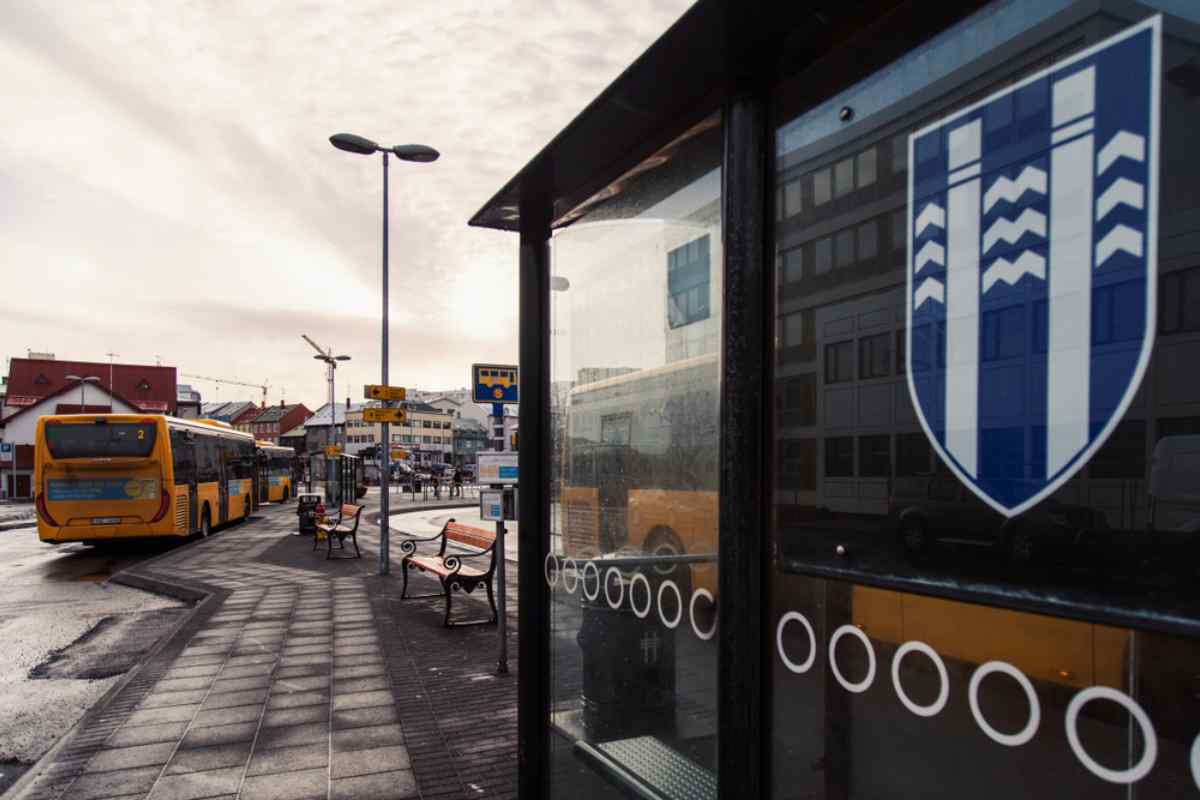 City bus service in Reykjavik Reykjavík city buses at a central stop by a shelter.
