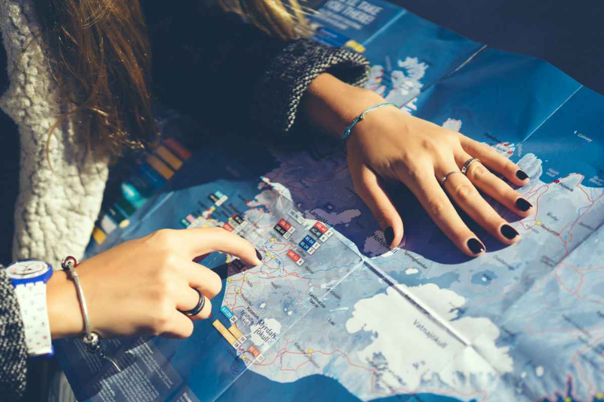 Girl chooses her next destination on a physical map of Iceland