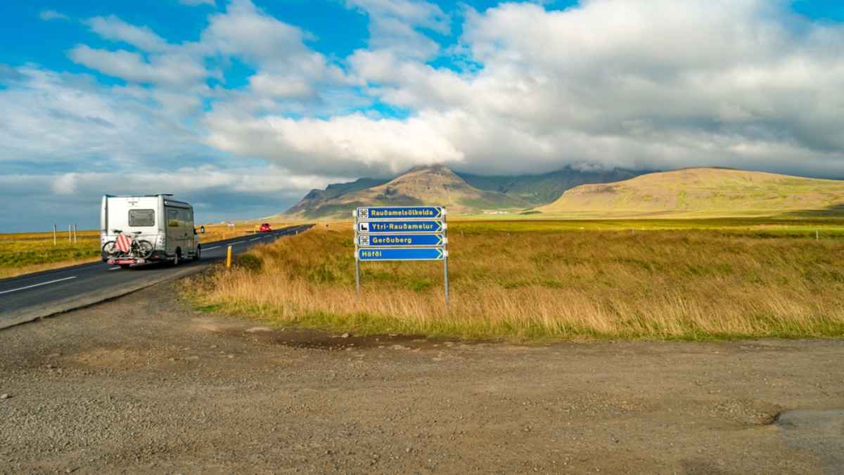 Road signs in Iceland as a white motorhome passes by.