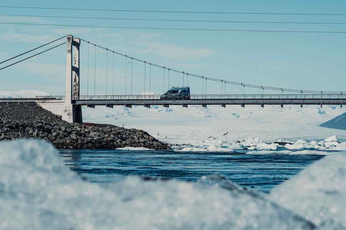 4x4 campervan in Iceland Campervan crossing a suspension bridge over an icy lagoon on a clear winter day in Iceland.