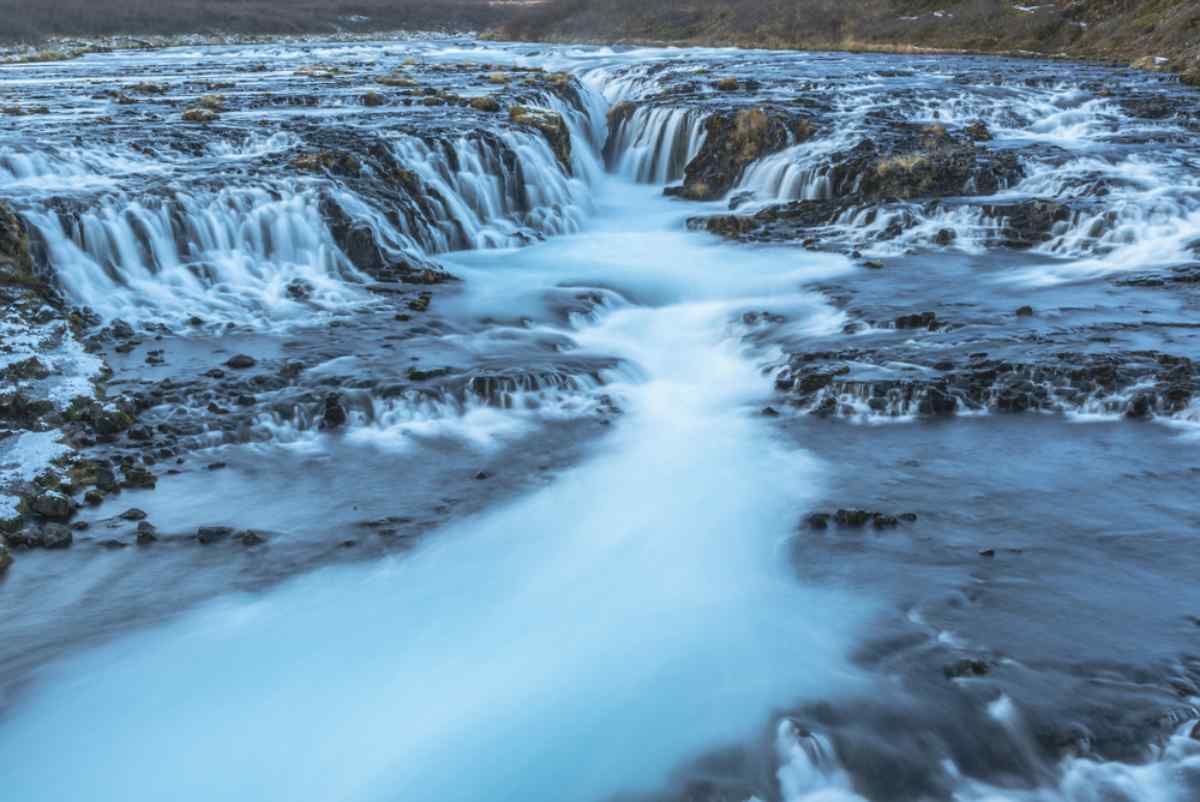 Brúarfoss waterfall Icy-blue cascades of Brúarfoss spilling over dark lava rock in winter.