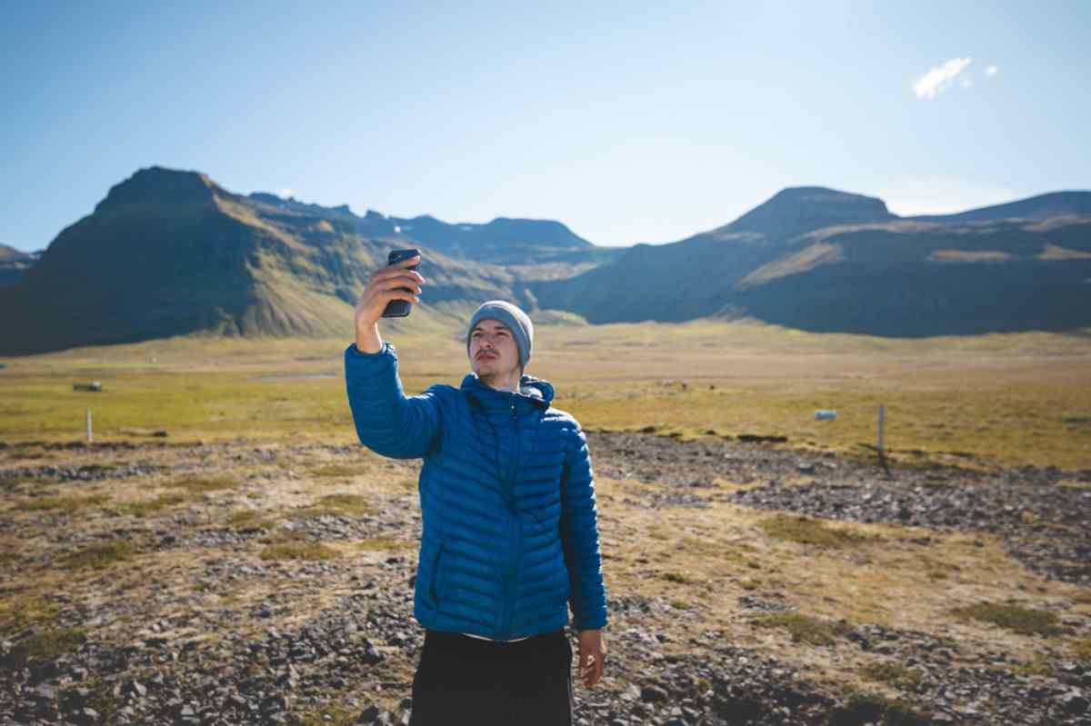 Checking signal in Iceland Traveler checking cell signal in a wide valley with sunlit mountains in the background.