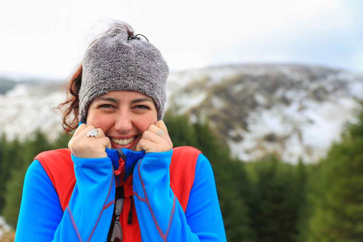 Traveler with layers in Iceland Smiling traveler bundled up in a beanie and midlayers on a chilly day outdoors.
