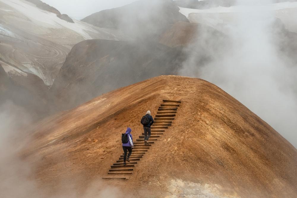 Best stops for Iceland in June Two hikers climbing up the stairs on a geothermal active area